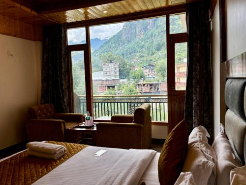 a room with a bed and a large window at Hotel Jogini Height's - Chandra A S Hospitality in Vashisht