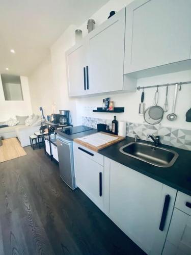 une cuisine avec des armoires blanches et un évier dans l'établissement Le Chic-Cadre Royal-Centre ville, à Sète