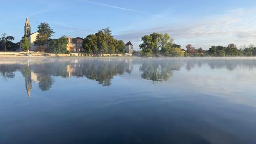 a misty lake with a church in the background at Villa la Rive, River Villa in Le Temple-sur-Lot