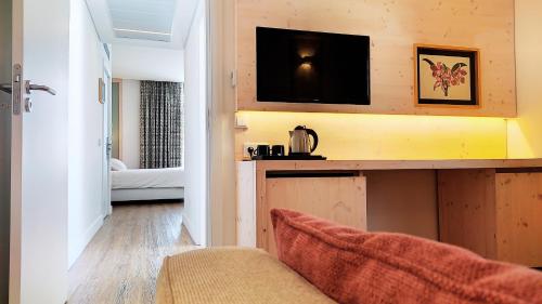 a living room with a couch and a television on a wall at Grande Hotel das Caldas da Felgueira in Caldas da Felgueira