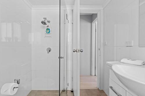 Un baño blanco con ducha y lavabo. en Parklea Sun Seabreeze The Entrance Sleeps 5, en The Entrance