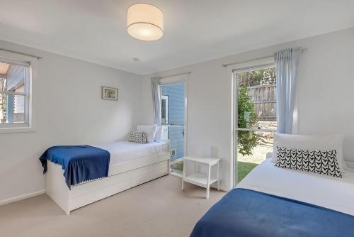 a white bedroom with two beds and a window at Stunning Coastal Home Views 1 Hour From Sydney in Wombarra