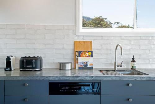 a kitchen with a sink and a counter top at Stunning Coastal Home Views 1 Hour From Sydney in Wombarra
