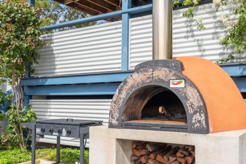 a pizza oven sitting next to a table at Stunning Coastal Home Views 1 Hour From Sydney in Wombarra