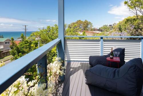 a balcony with two chairs and a table with a glass of wine at Stunning Coastal Home Views 1 Hour From Sydney in Wombarra