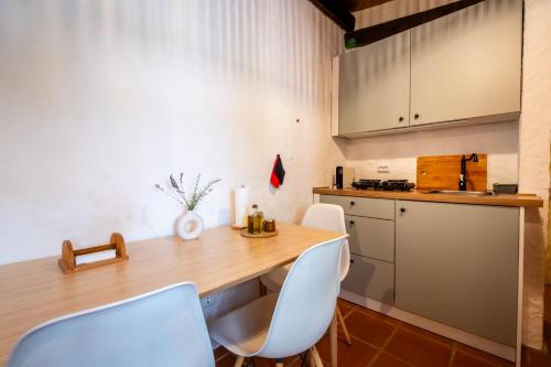 a kitchen with a wooden table and white chairs at Riverlake House - frente ao lago e com jardim in Vila de Rei