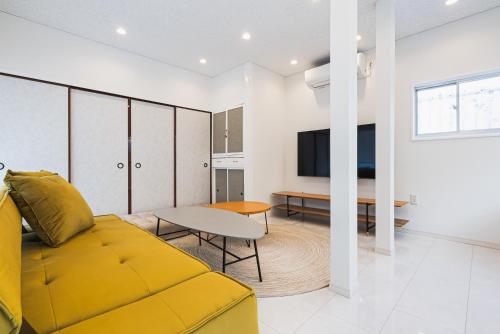 a living room with a yellow couch and a table at Villa Myoden in Ichikawa