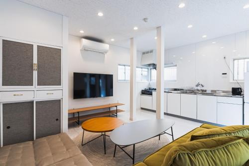 a living room with a couch and a table and a kitchen at Villa Myoden in Ichikawa