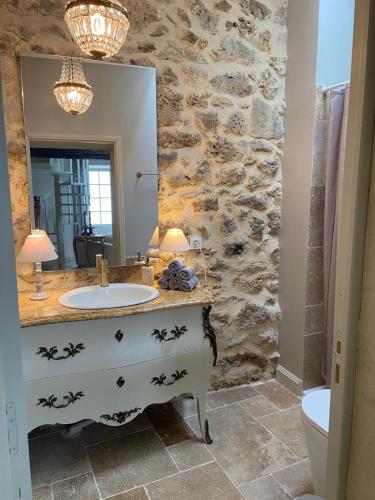 une salle de bain avec un lavabo et un mur en pierre dans l'établissement Clos Stella, à Mérignas