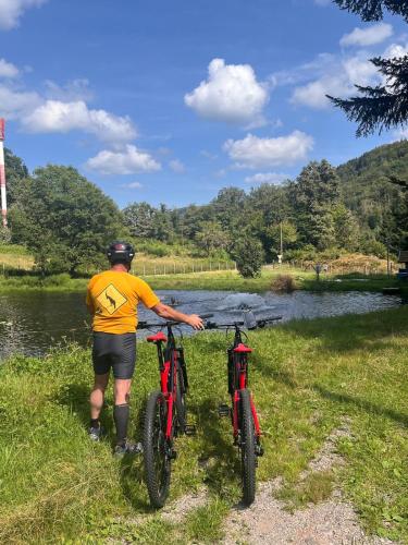 a man standing next to two bikes next to a river at gite du Breuchin 2 in La Longine