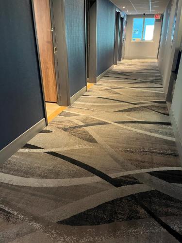an empty hallway in an office building with shadows on the floor at Super 8 by Wyndham Cornwall ON in Cornwall