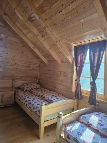 a bedroom with two beds in a log cabin at Konaci Očeva Zemlja Vikendica i Bungalovi in Mojkovac