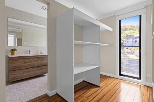 un bagno bianco con lavandino e specchio di Lakeview Oasis on The Esplanade a Warners Bay