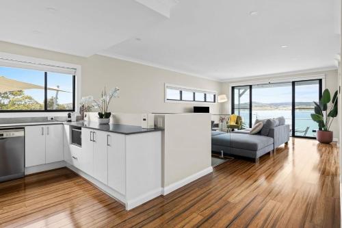 a kitchen with white cabinets and a living room with a couch at Lakeview Oasis on The Esplanade in Warners Bay