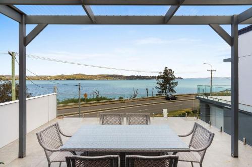 a table and chairs on a balcony with a view of the water at Lakeview Oasis on The Esplanade in Warners Bay