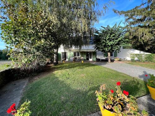 une maison blanche avec une cour ornée de fleurs rouges dans l'établissement Casa Rivage, à Chalonnes-sur-Loire