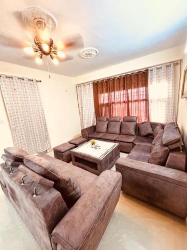 a living room with a brown couch and a table at Ashiana at Ivy Apartments in Solan