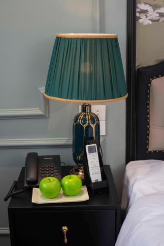 a lamp on a table with a telephone and green apples at Madelise Palace Hotel & Travel in Hanoi
