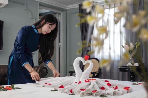 a woman making a wedding cake with swans on a table at Madelise Palace Hotel & Travel in Hanoi