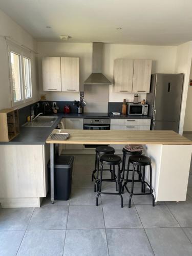 - une cuisine avec un comptoir en bois et des tabourets dans l'établissement Villa proche des plages avec Jaccusi, à Saubion