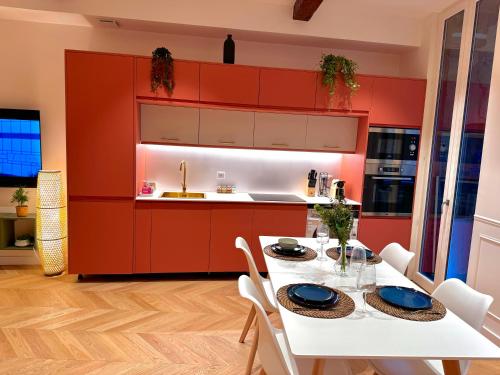 une cuisine avec des placards rouges, une table blanche et des chaises dans l'établissement Appartement au cœur de Toulouse, à Toulouse