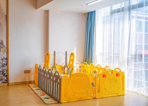 a yellow crib in a room with a window at Zhangjiajie DreamWay Hotel - Free pick up service in Zhangjiajie