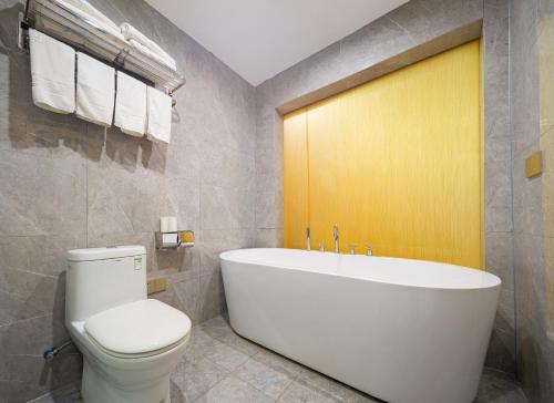 a bathroom with a white tub and a toilet at Zhangjiajie DreamWay Hotel - Free pick up service in Zhangjiajie