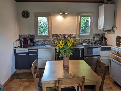 une cuisine avec une table en bois et un vase de fleurs. dans l'établissement Maison au calme en Dordogne, à Trémolat