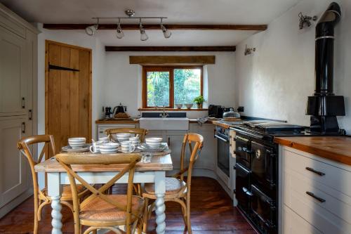 a kitchen with a table with chairs and a stove at The Old Coach House - Converted barn with private garden parking and fireplace in Totnes