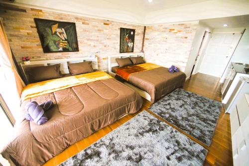 a bedroom with two beds and a brick wall at Beach front Apartment with Sea View VIP CONDOCHAIN in Rayong