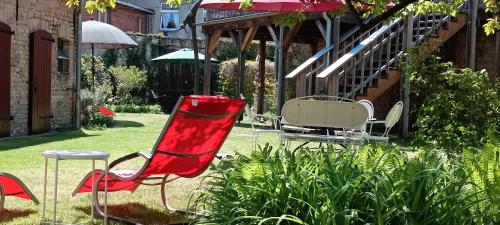a red chair sitting in a yard with an umbrella at SchlossparkFerienwohnungen Rheinsberg mit Garten in Rheinsberg