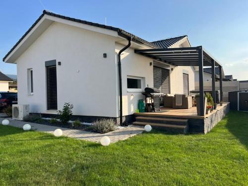 a white house with a deck in a yard at Moderny luxusny domcek s vyhladom na zamok in Prievidza