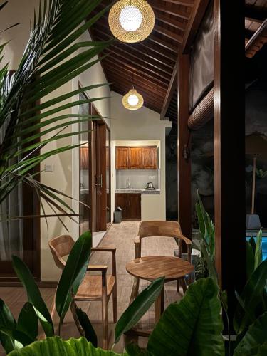 a living room with a table and chairs and plants at Cempaka Kembar Ubud in Ubud