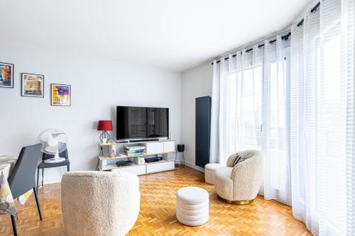 un salon avec deux chaises et une télévision dans l'établissement GuestReady - Séjour familial dans le 20ème, à Paris