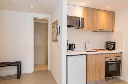 a small kitchen with a sink and a microwave at Austral Departamentos in Ushuaia