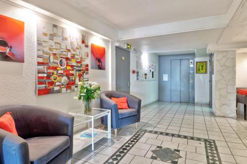 - un hall avec deux chaises et une table avec un vase de fleurs dans l'établissement Résidence Pierre & Vacances Bandol Port, à Bandol