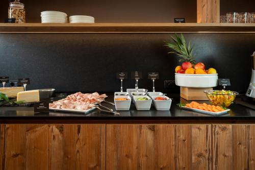 a buffet with meat and fruit on a table at Hotel La Maison Wellness & Spa in Alleghe