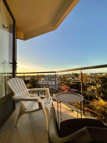 a balcony with two white chairs and a table at Sea View 2-Bedroom Apt, 10mins Walk to Beach - GBHC7 in The Vale