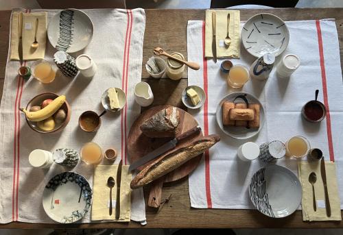 einen Tisch mit Tellern und Küchenutensilien auf dem Tisch in der Unterkunft Le 16 maison d'hôtes en Berry in Henrichemont