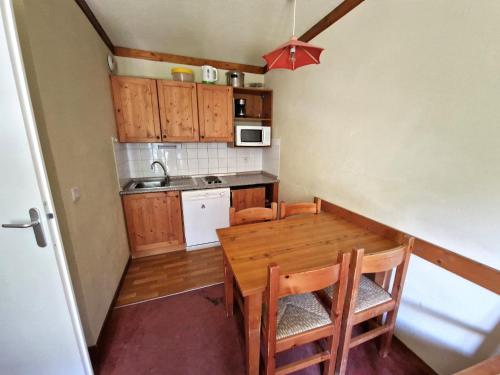 une petite cuisine avec une table et des chaises en bois dans l'établissement T2 pour 4 personnes, à 30m des pistes et des commerces, Valfréjus - FR-1-265-207, à Valfréjus