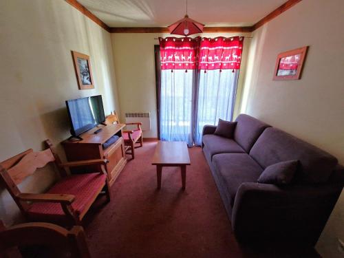 un salon avec un canapé et une télévision dans l'établissement T2 pour 4 personnes, à 30m des pistes et des commerces, Valfréjus - FR-1-265-207, à Valfréjus