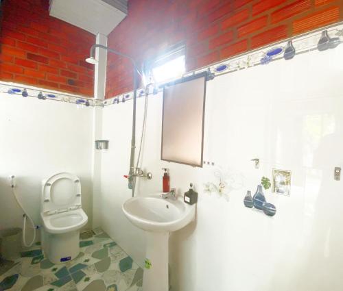 a bathroom with a white toilet and a sink at Cat Tien Backpackers Hostel in Cat Tien