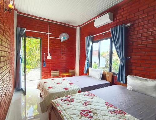 a bedroom with two beds and a brick wall at Cat Tien Backpackers Hostel in Cat Tien