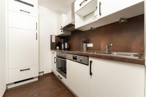 a kitchen with white cabinets and a sink at Berghof Sölden - anno 1588 in Sölden