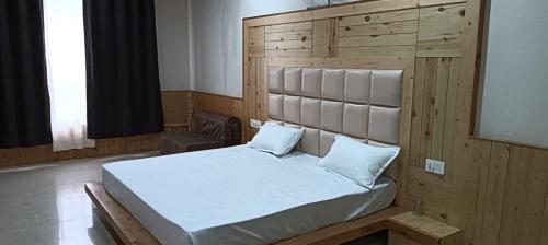 a bedroom with a large bed with a wooden headboard at HOTEL ROSHAN REGENCY By seraj heritage in Shamshi