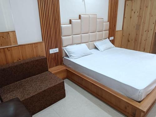a bedroom with a large bed and a bench at HOTEL ROSHAN REGENCY By seraj heritage in Shamshi