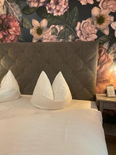 a white bed with a flower mural on the wall at Gästehaus Weiherhof in Alpbach