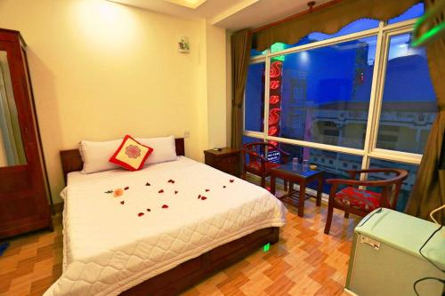 a bedroom with a bed and a window with flowers on it at Sun Sea Hotel in Quy Nhon