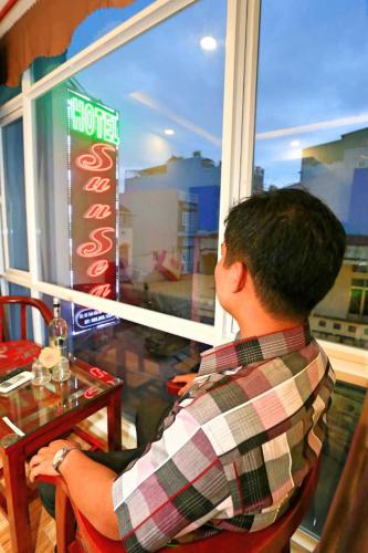 a man sitting at a table looking out of a window at Sun Sea Hotel in Quy Nhon