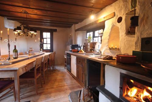 a kitchen with a long table and a fireplace at Chalets Casa da Luzi in Surcasti